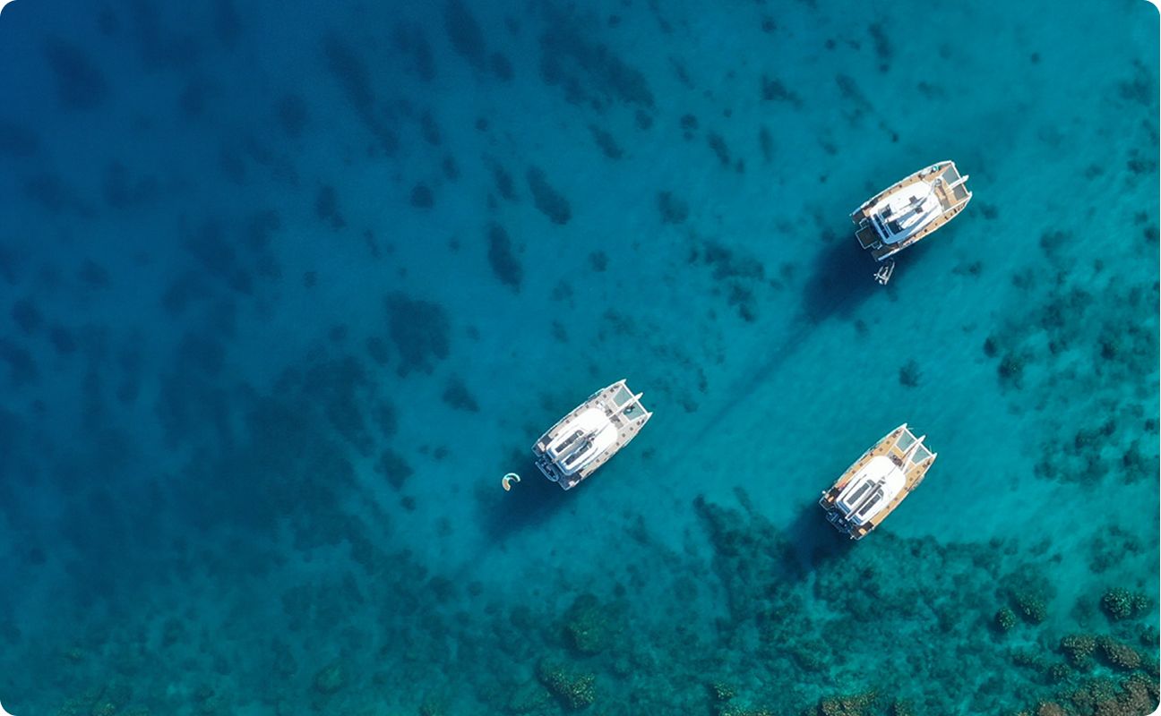Two catamarans at anchor over a turquoise seabed