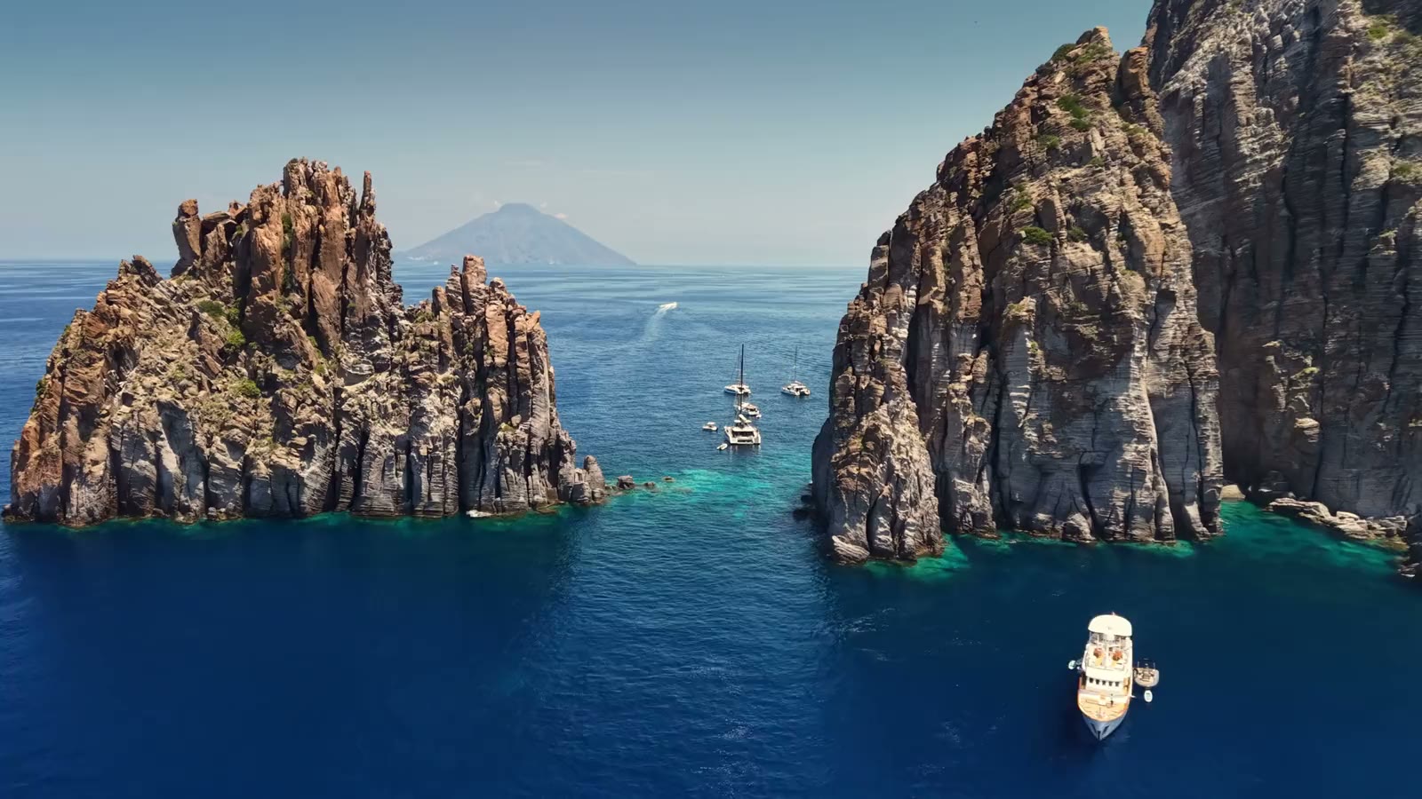 Catamarans anchored in a cove between cliffs