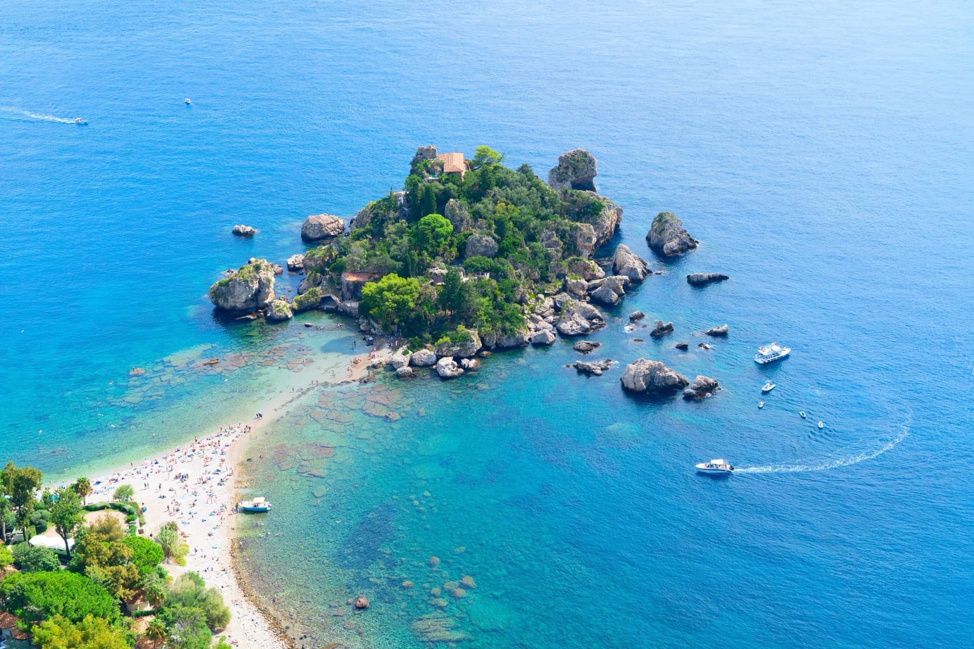 Aerial view of a Sicilian bay with turquoise waters and an anchored boat