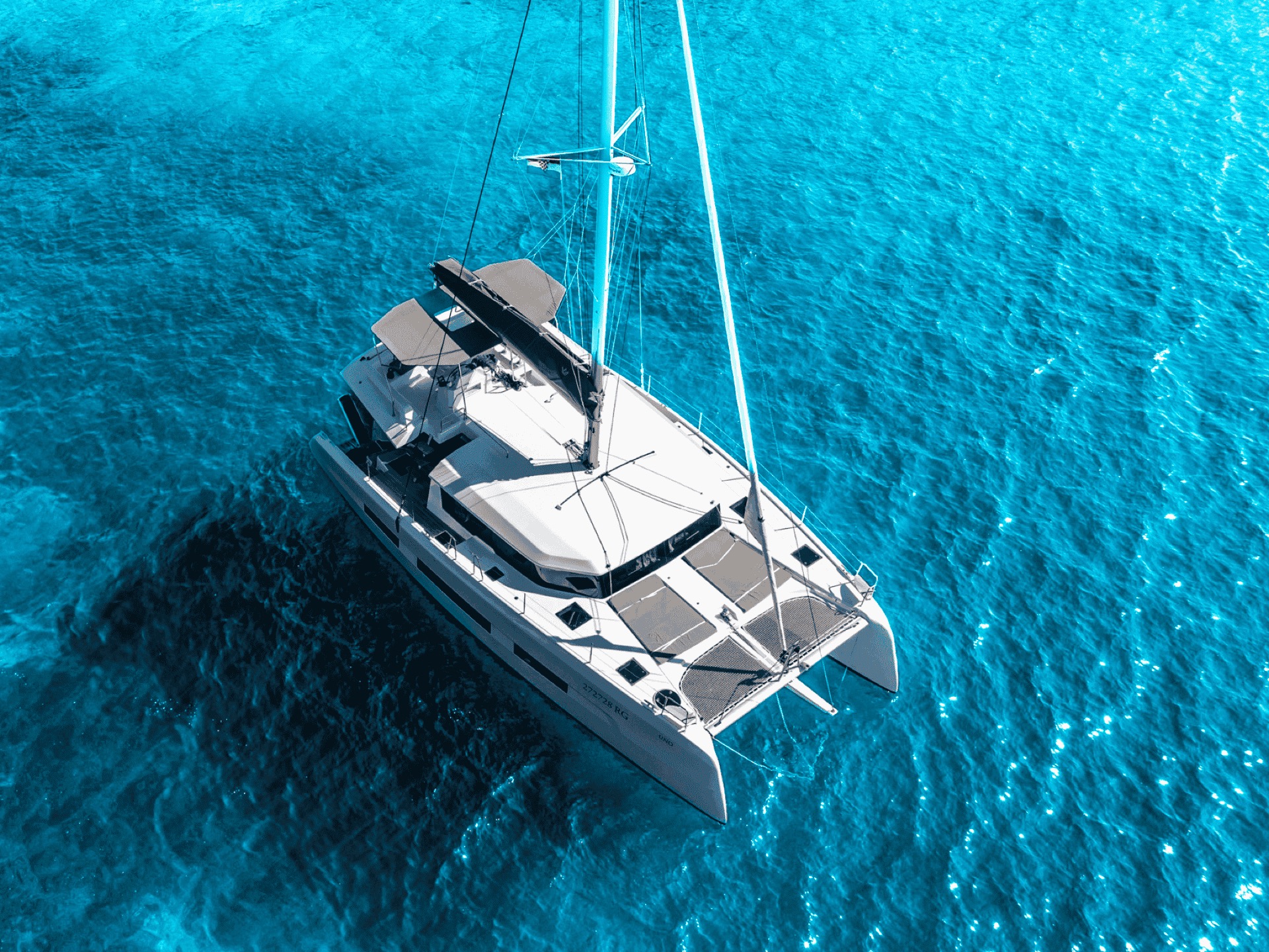 Catamaran at anchor in crystal-clear waters with guests on board